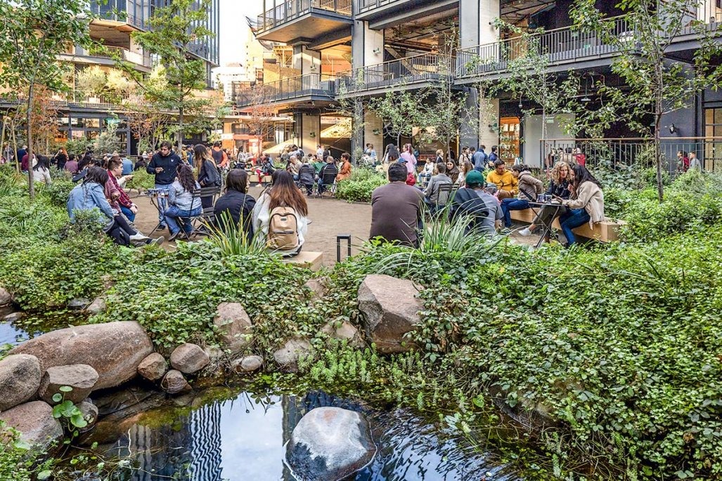 Plaza-jardín urbana con personas reunidas entre vegetación